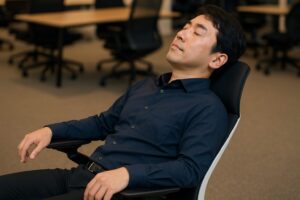 スチールケース ジェスチャーに深くリクライニングし、背もたれの滑らかな追従機能でリラックスする日本人。