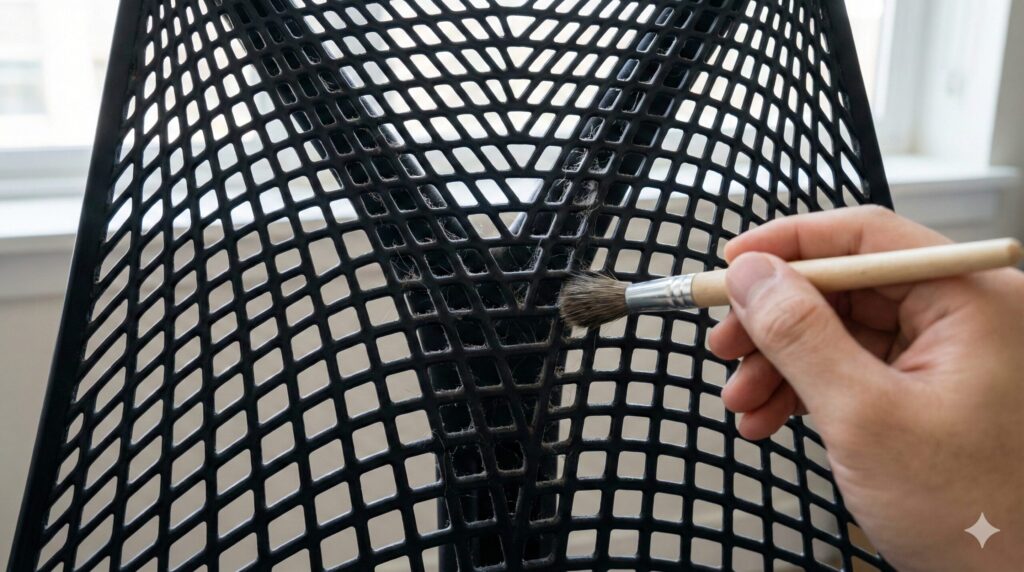 セイルチェアの背面メッシュの網目にホコリが溜まり、ブラシで掃除をしている様子。メンテナンスの手間を示す実例。